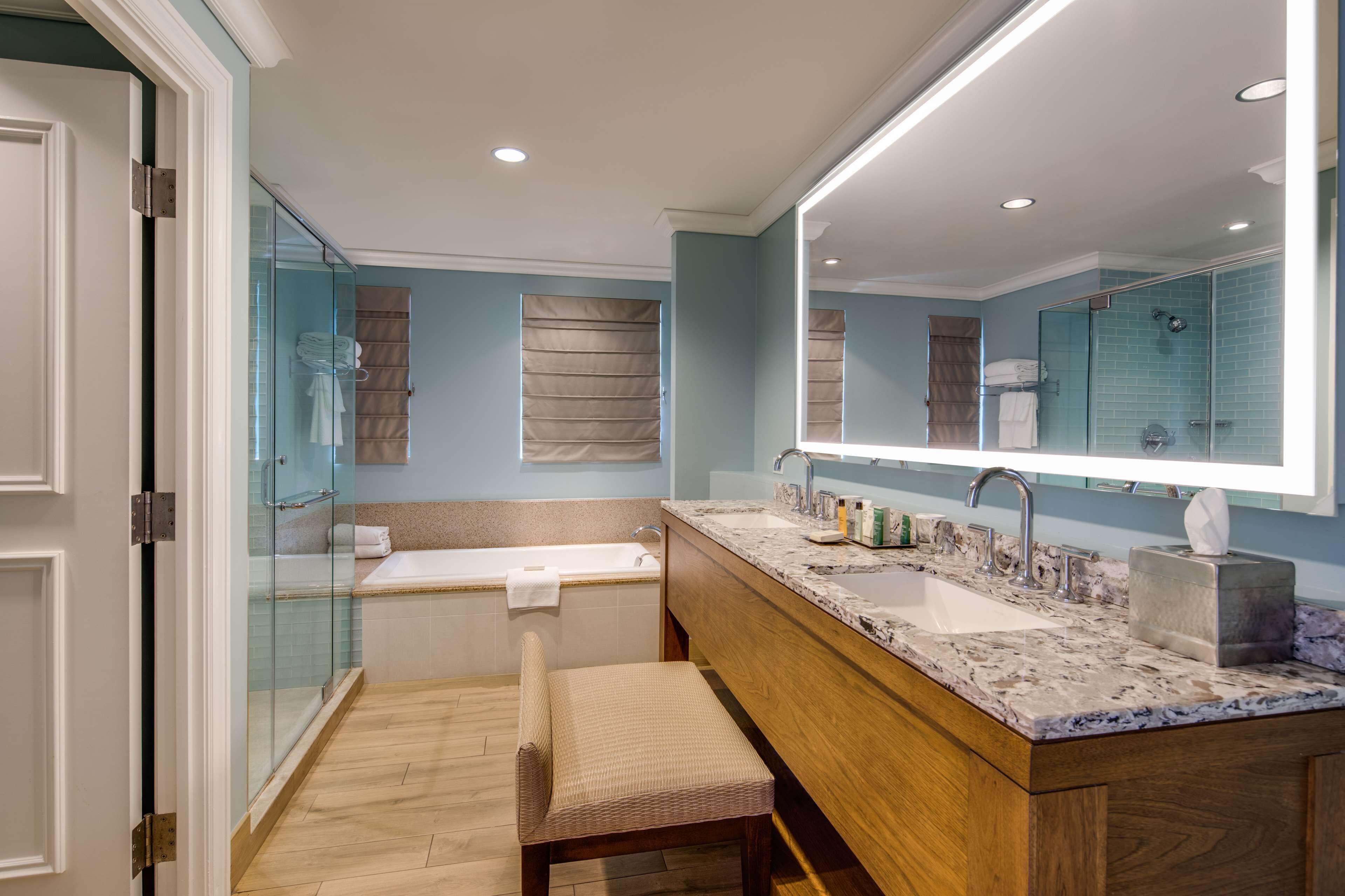A modern bathroom with a glass shower enclosure, a wooden vanity, and a large mirror.