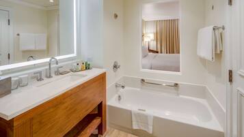 Un baño moderno con un espejo grande, dos lavamanos, una bañera y un mueble de tocador de madera.