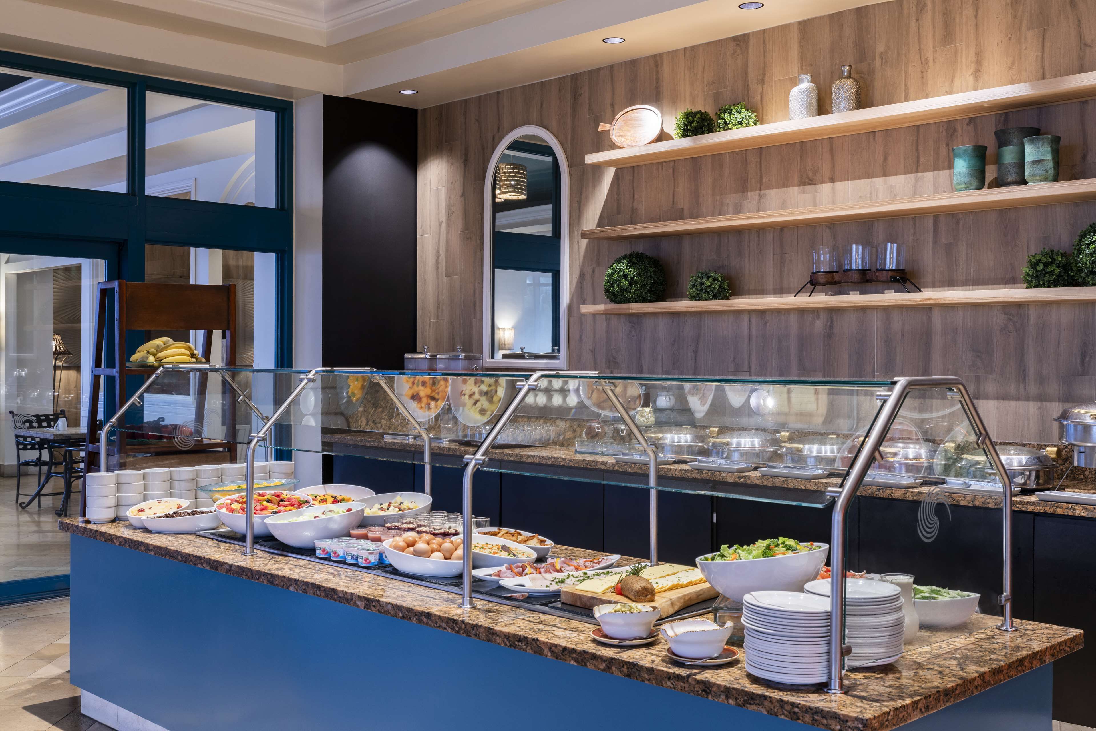 A buffet area with various food options, a seating area with chairs, and a decorative wall with shelves.