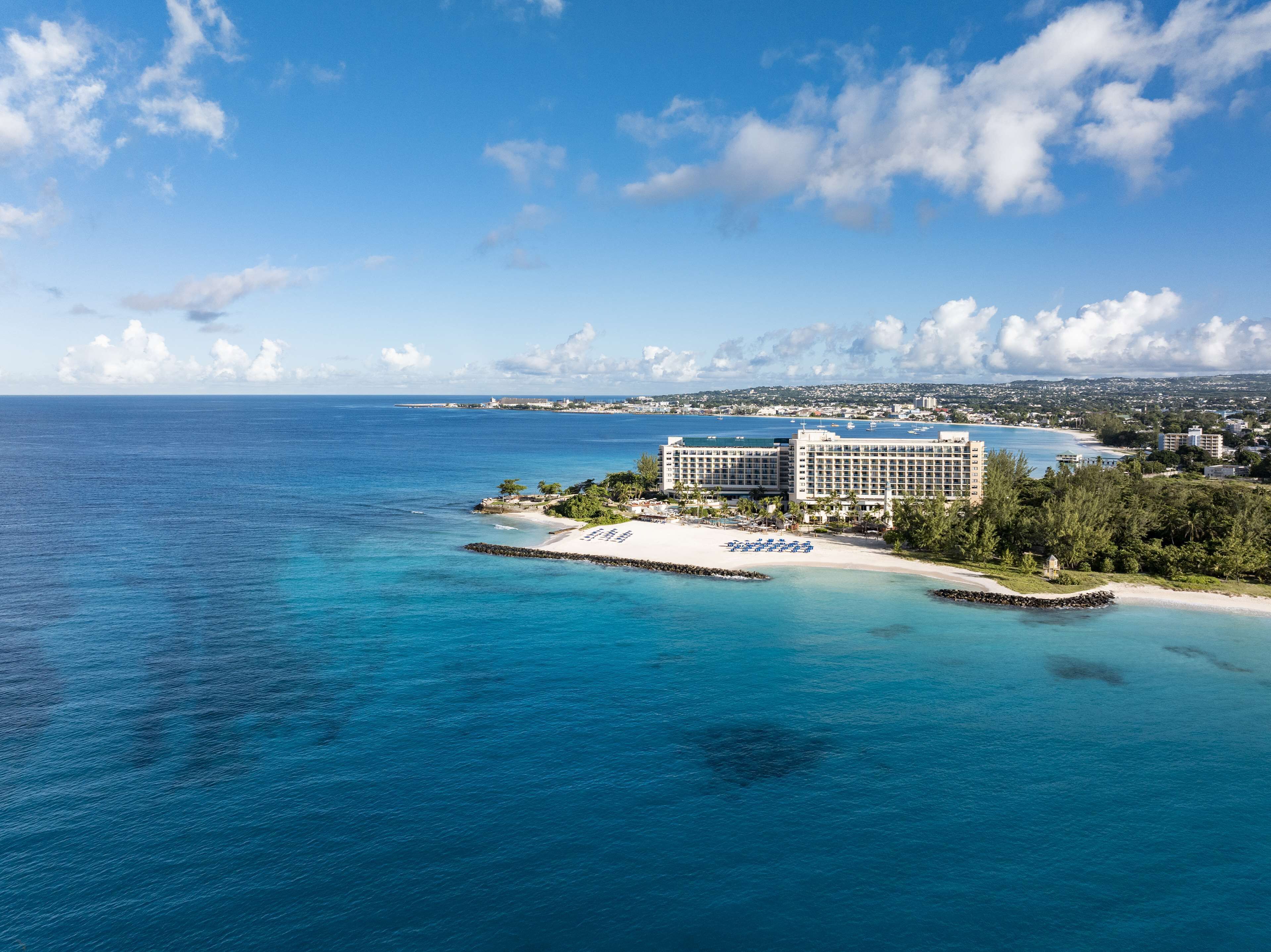 A coastal hotel with a beach, ocean view, and a large building with multiple floors.