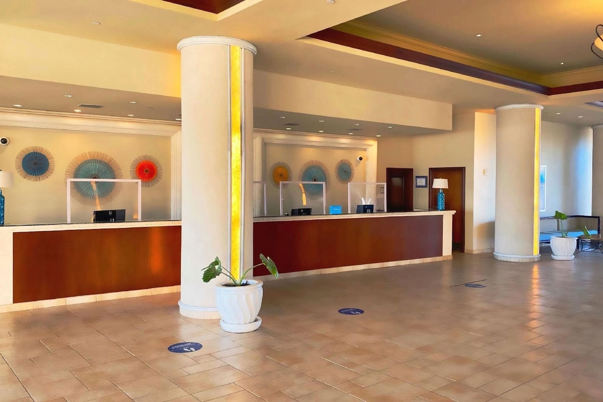 A hotel reception area with a reception desk, two large columns, and decorative wall art.