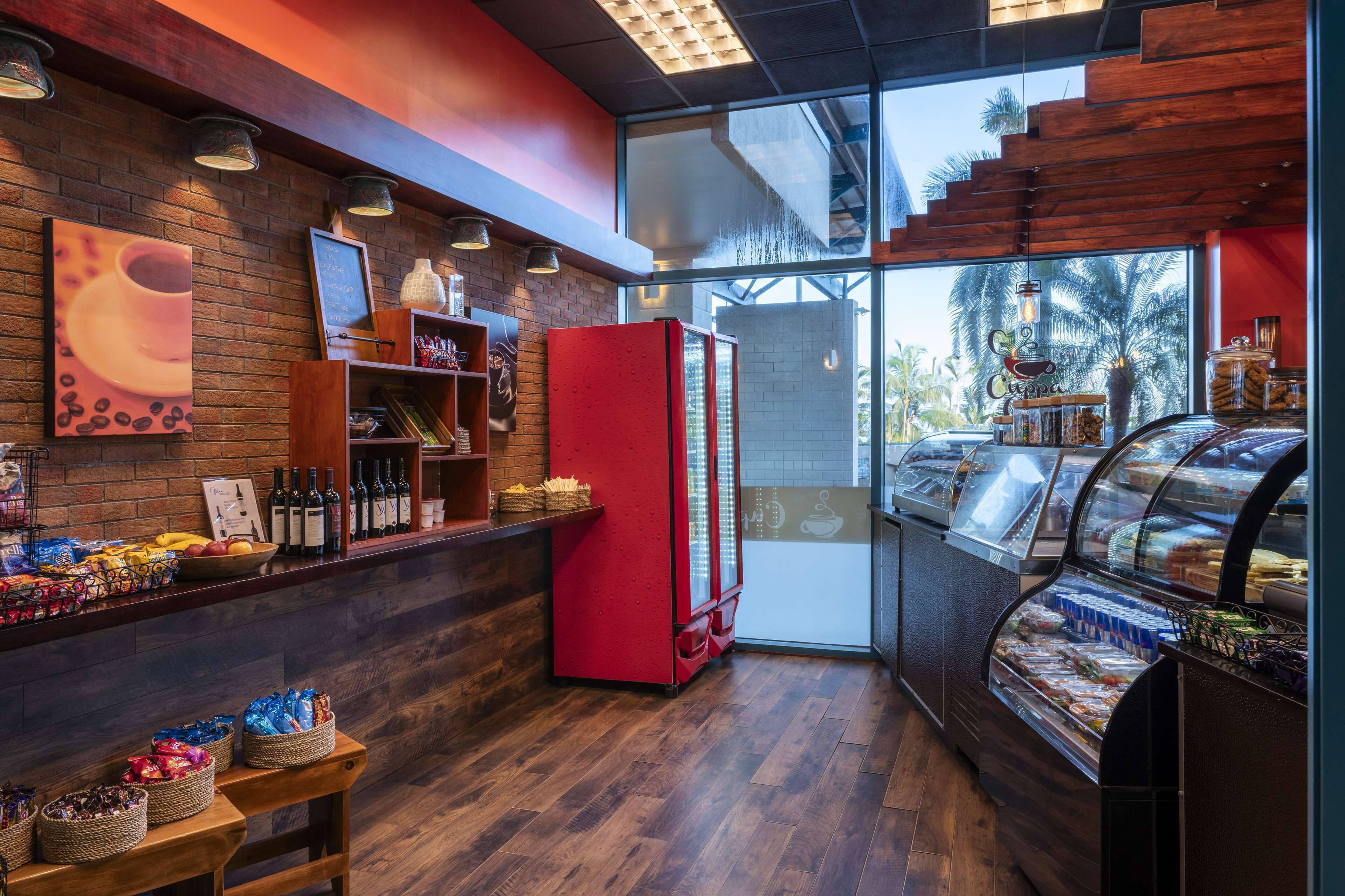 A bakery counter with a red refrigerator, a display case with pastries, and a wooden counter with various items.
