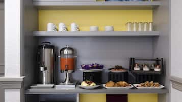 Una barra de desayuno compacta con cafetera, mini refrigerador y diversas opciones para el desayuno.