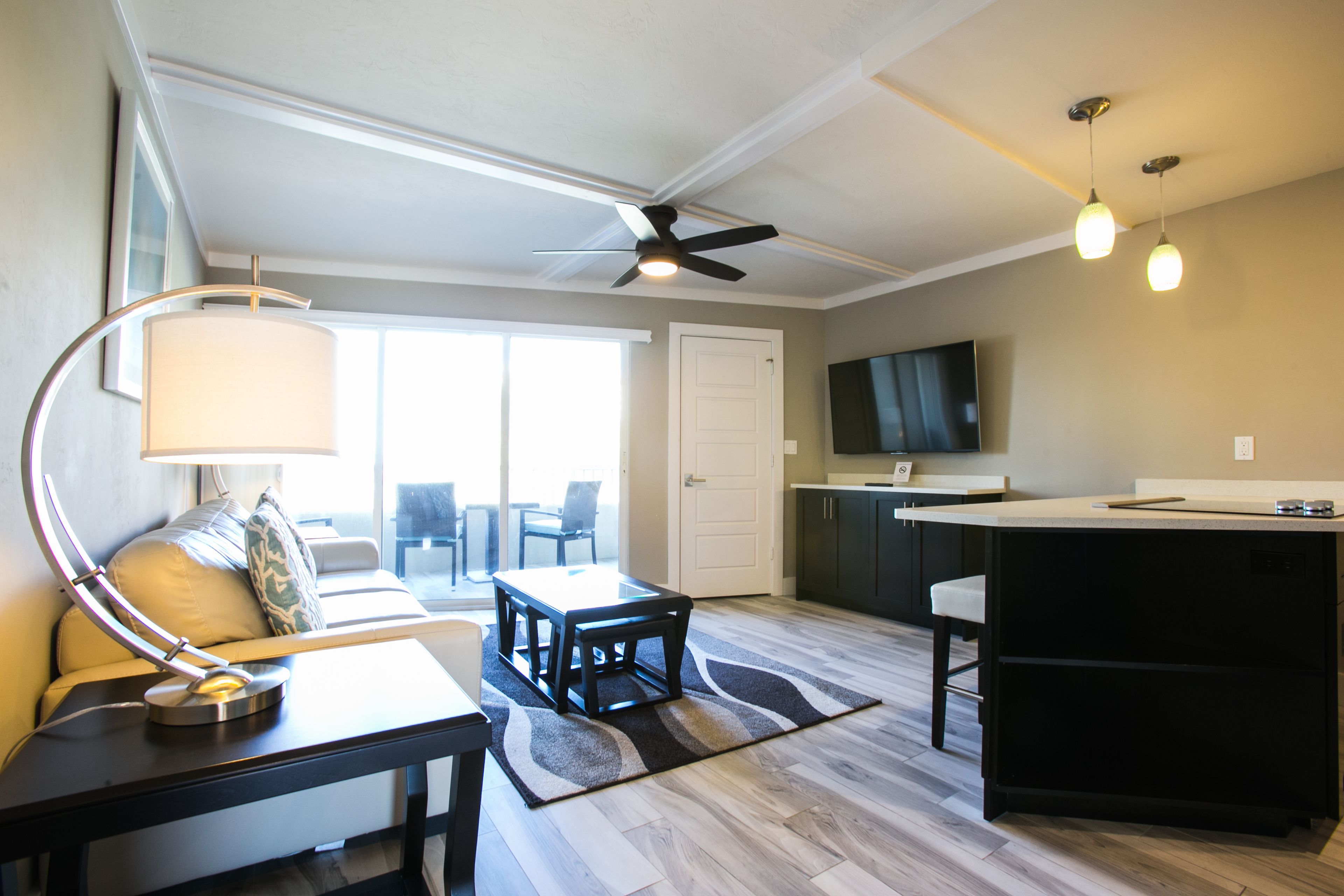 A modern living room with a dining area, a kitchen, and a large TV.