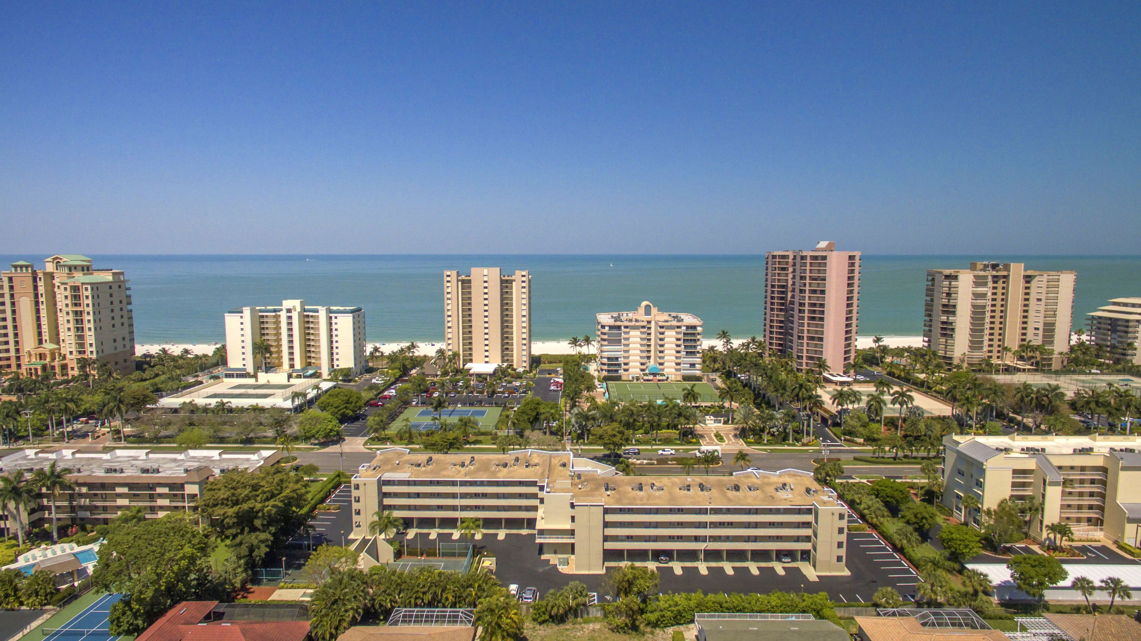 Un complex hoteler a la costa amb diversos edificis alts, una zona d'aparcament i vistes a l'oceà.