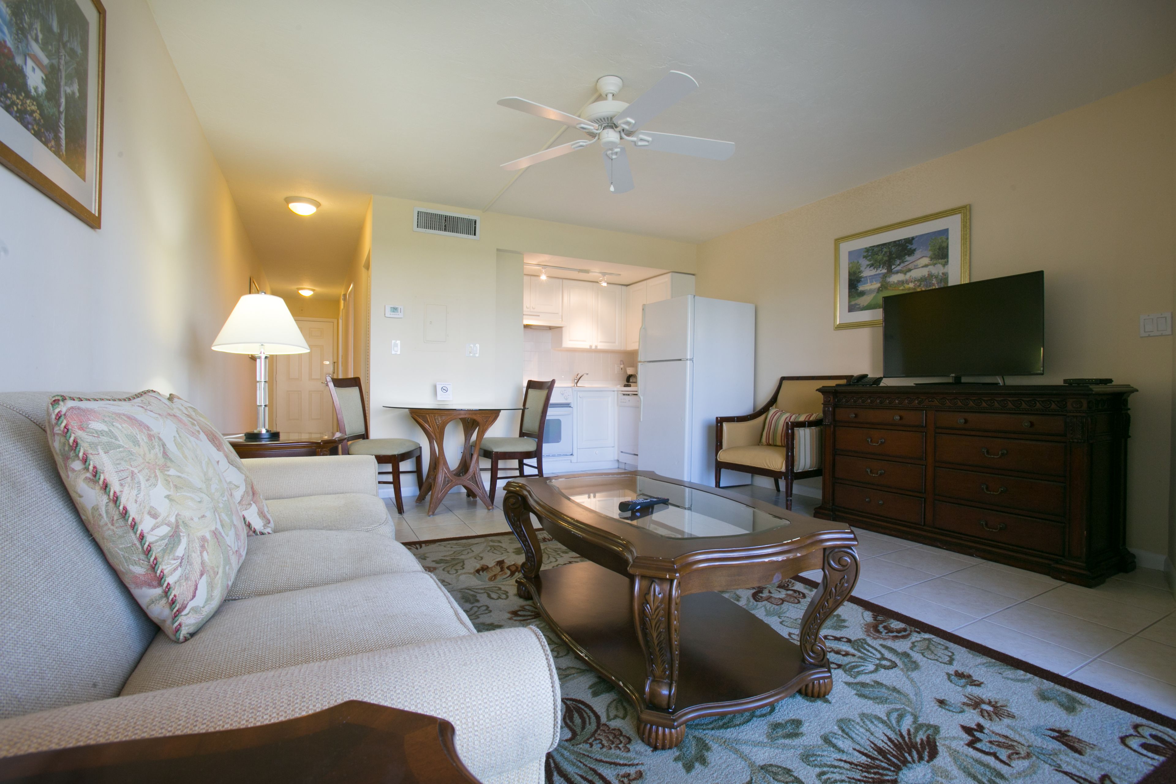 A living room with a sofa, coffee table, TV, and a dining area with chairs and a table.