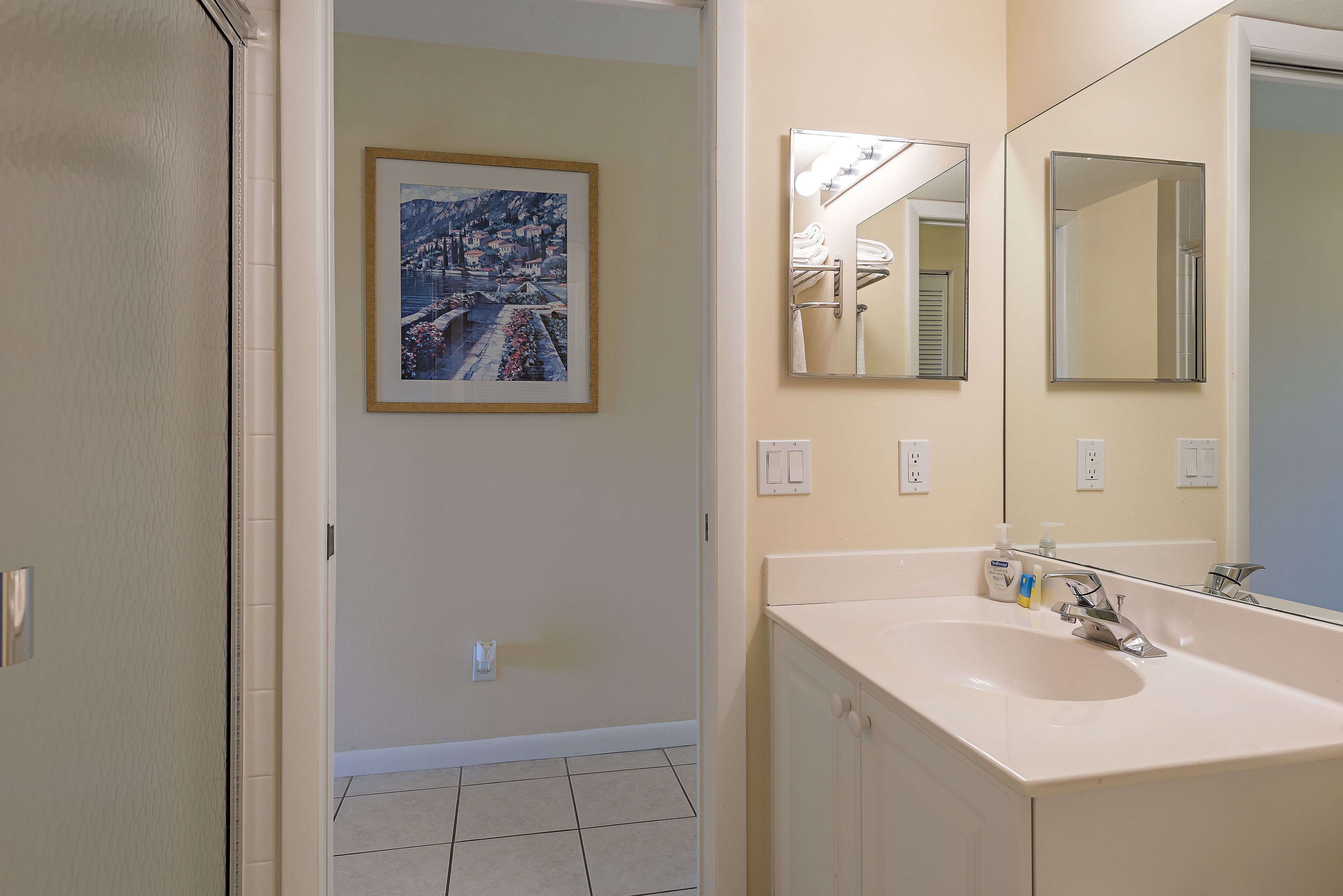 Un bagno con uno specchio grande, un lavandino e un quadro appeso alla parete.