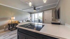 A modern kitchen with a central island, pendant lighting, and a ceiling fan. - Marco Beach Vacation Suites (Marco Island)