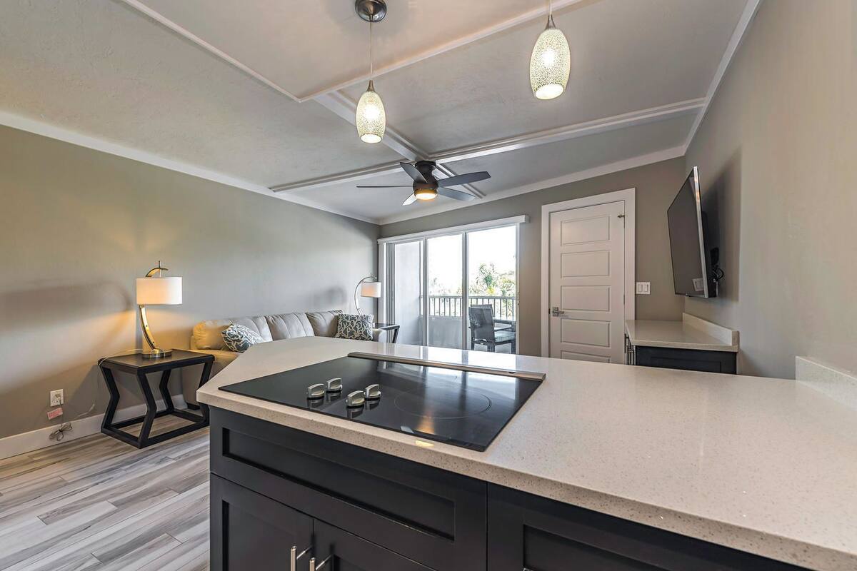 A modern kitchen with a central island, pendant lighting, and a ceiling fan.