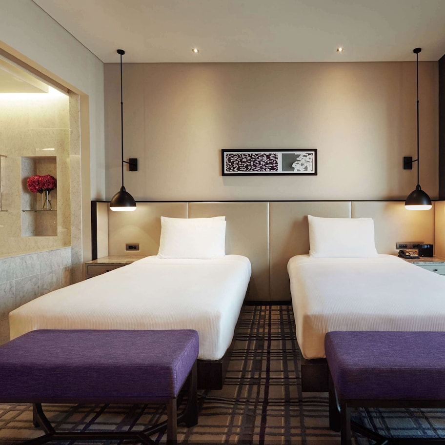 A hotel room with two beds, a bathroom, and a small sitting area.