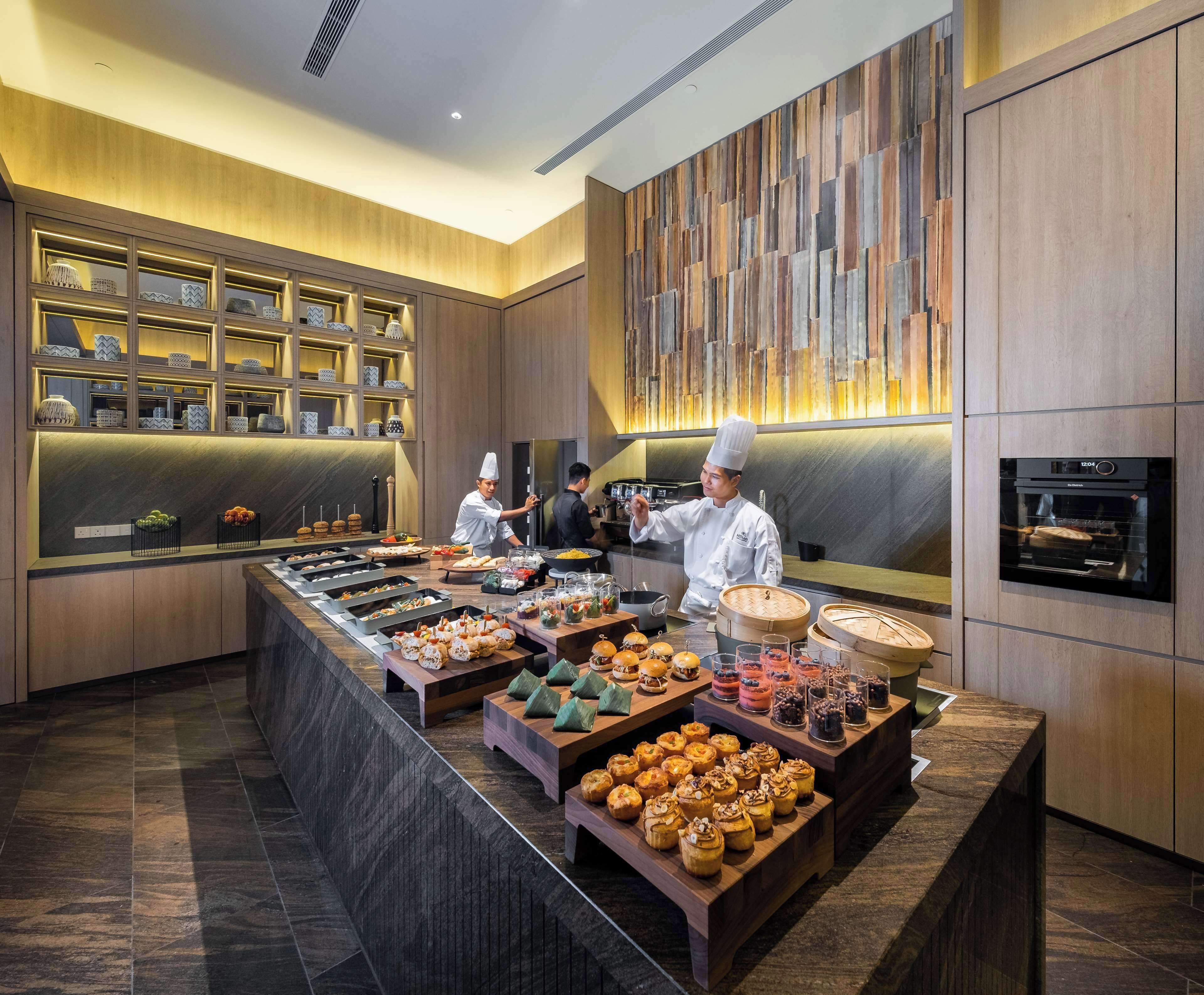 Un espace buffet proposant une variété de plats et où des chefs préparent les aliments.