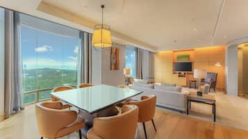 Een moderne hotelkamer met een grote eettafel, comfortabele zithoek, een bank en een televisie.
