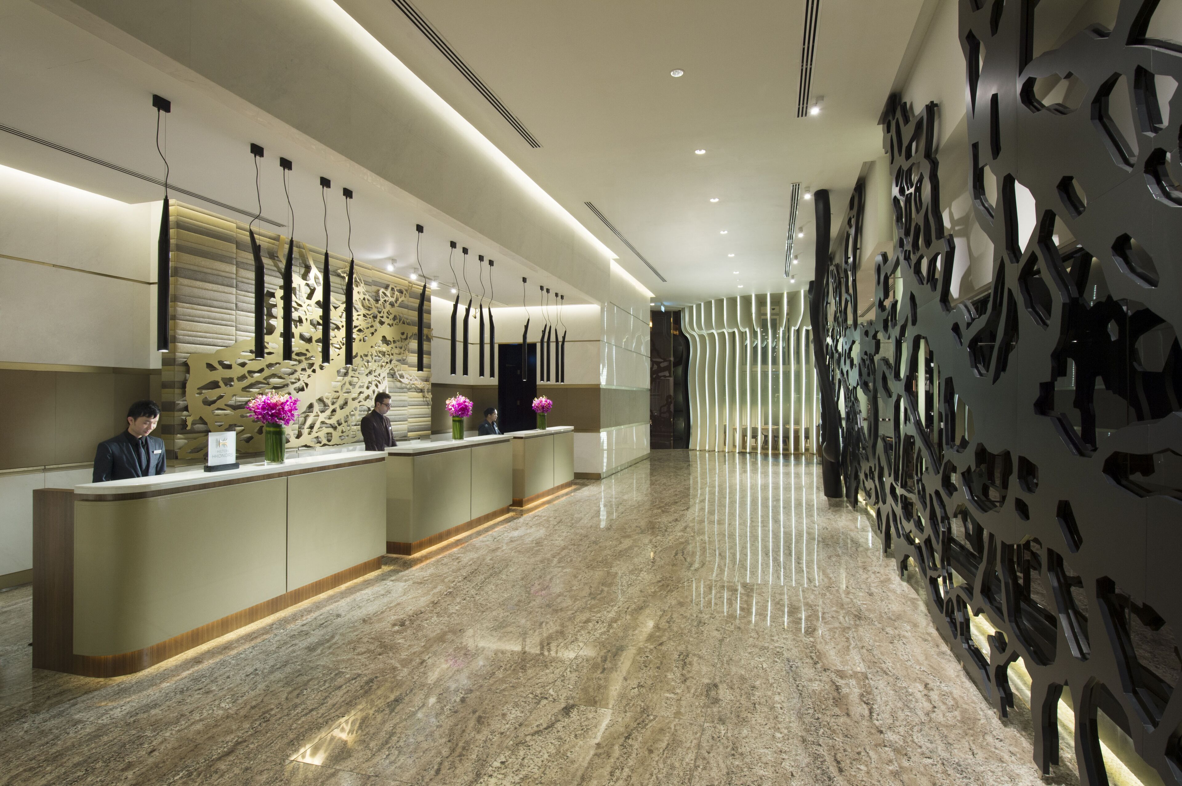 A modern reception area with a marble floor, a reception desk, and decorative wall panels.