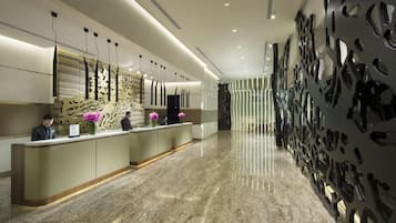 A modern reception area with a marble floor, a reception desk, and decorative wall panels.