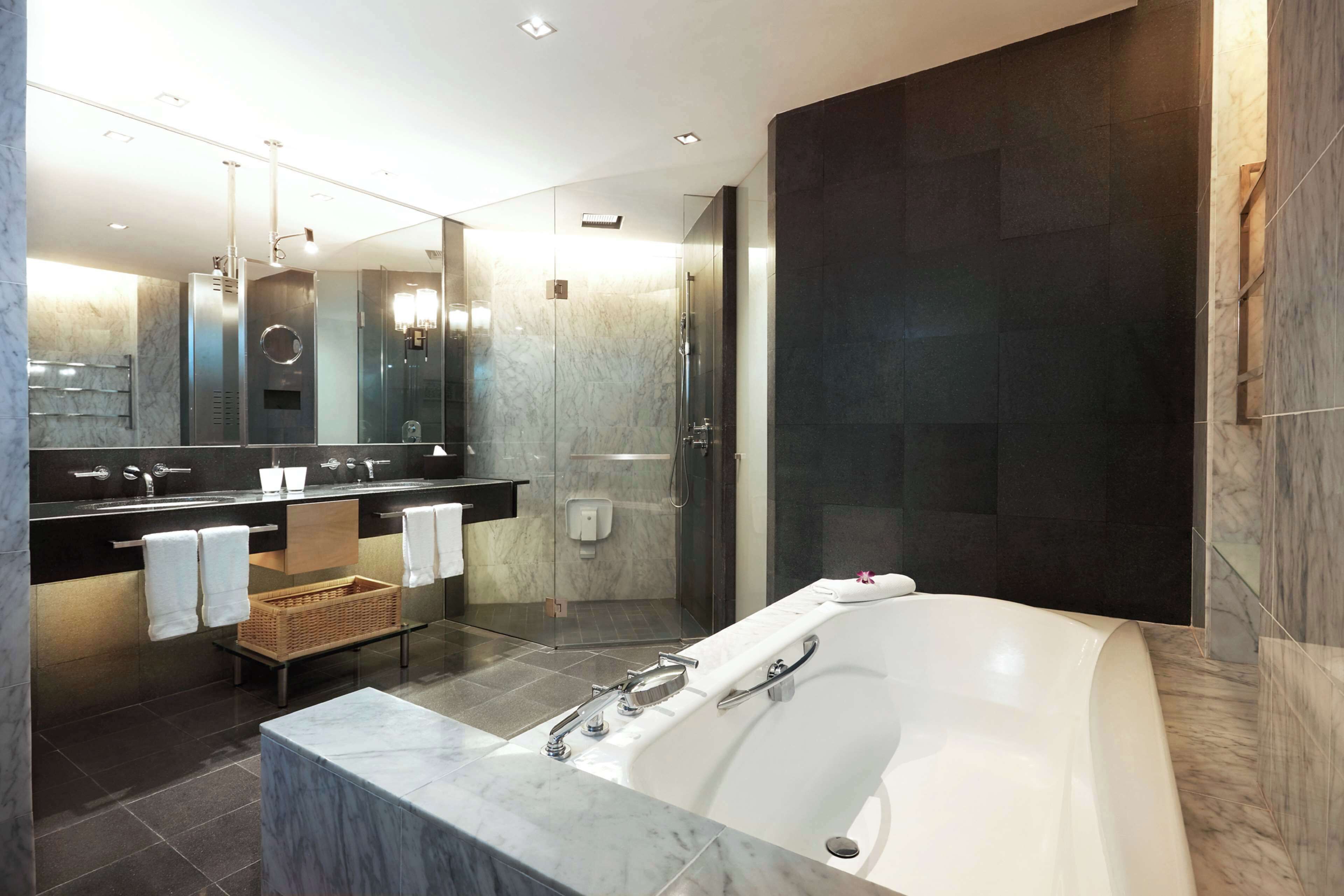 Une salle de bain moderne dotée d’une grande baignoire, d’une douche séparée et d’un meuble-lavabo avec un miroir.