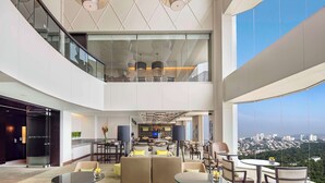 A modern hotel lobby with a high ceiling, glass railings, and a city view. - Hilton Kuala Lumpur (Kuala Lumpur)