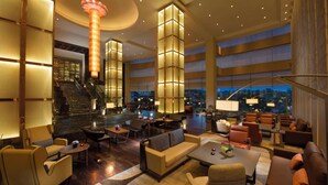 A spacious lobby with a grand staircase, multiple seating areas, and large windows offering views of the cityscape. - Hilton Kuala Lumpur (Kuala Lumpur)