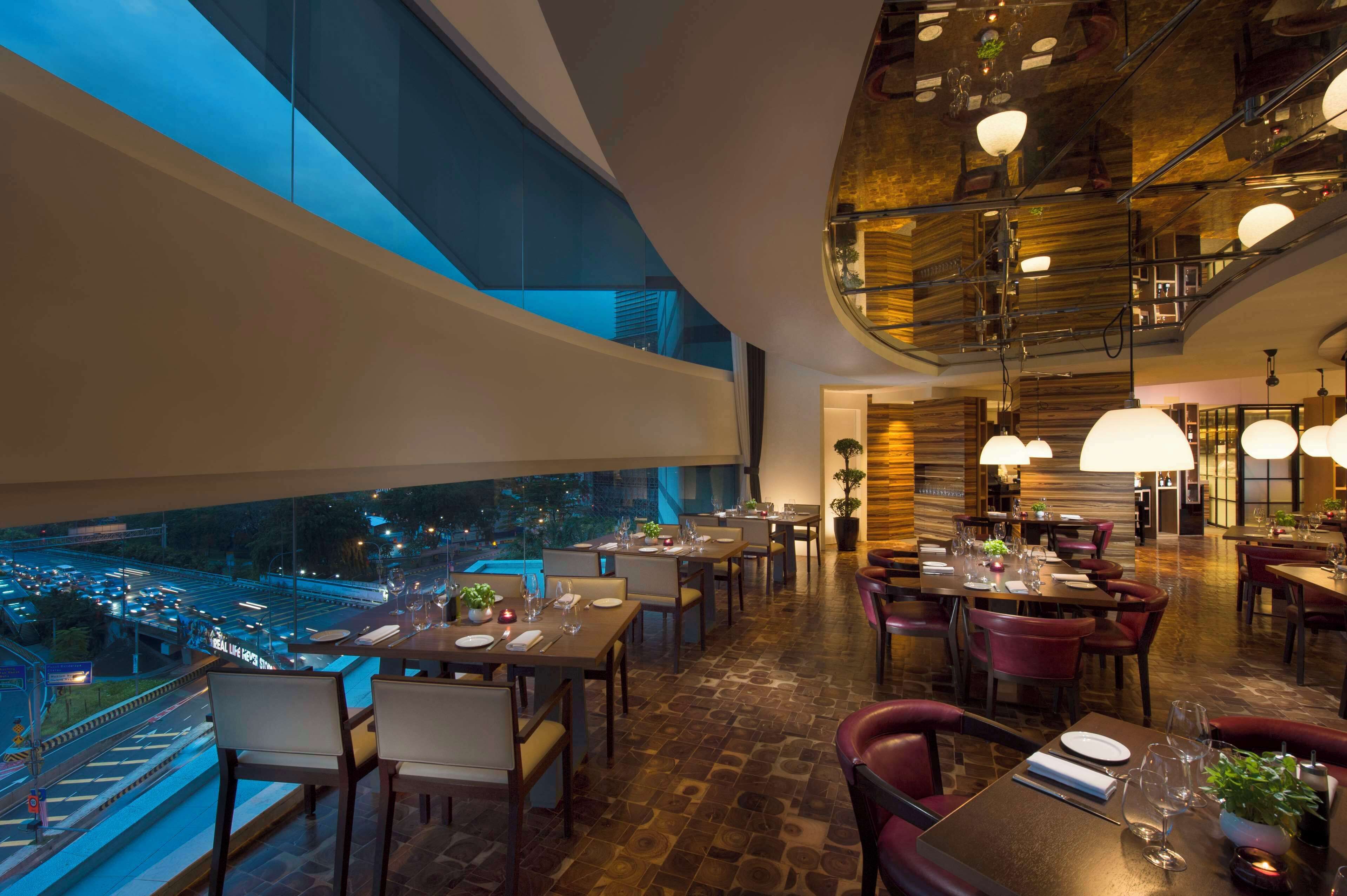 A restaurant with tables set for dining, large windows overlooking a cityscape, and a modern interior design.