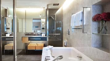 A modern bathroom with a large bathtub, a glass-enclosed shower, and a vanity with a mirror.