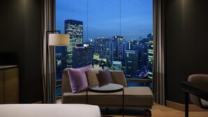 A modern hotel room with a large window offering a city view at dusk. - Hilton Kuala Lumpur (Kuala Lumpur)