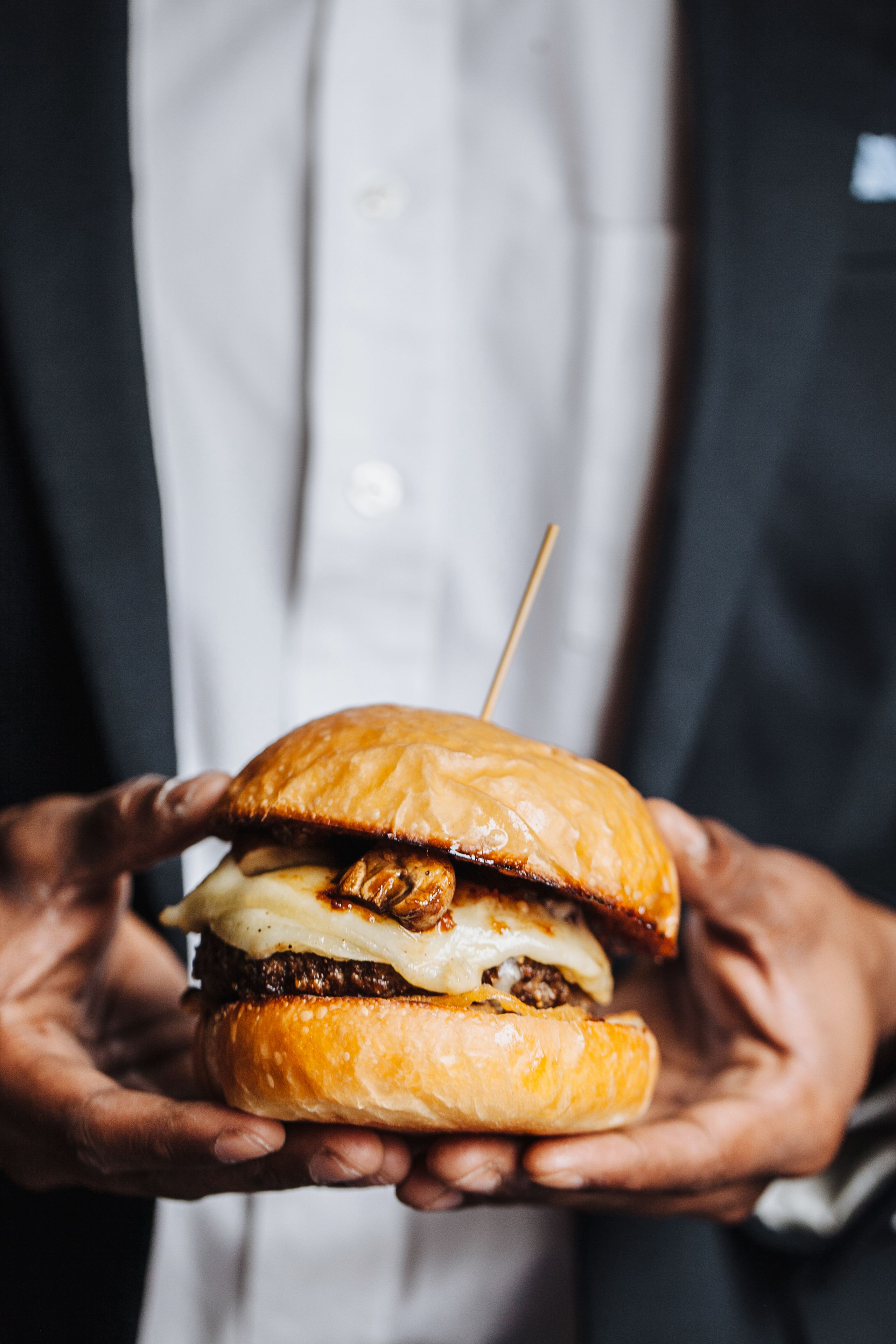 A person holding a sandwich with a toothpick in it.