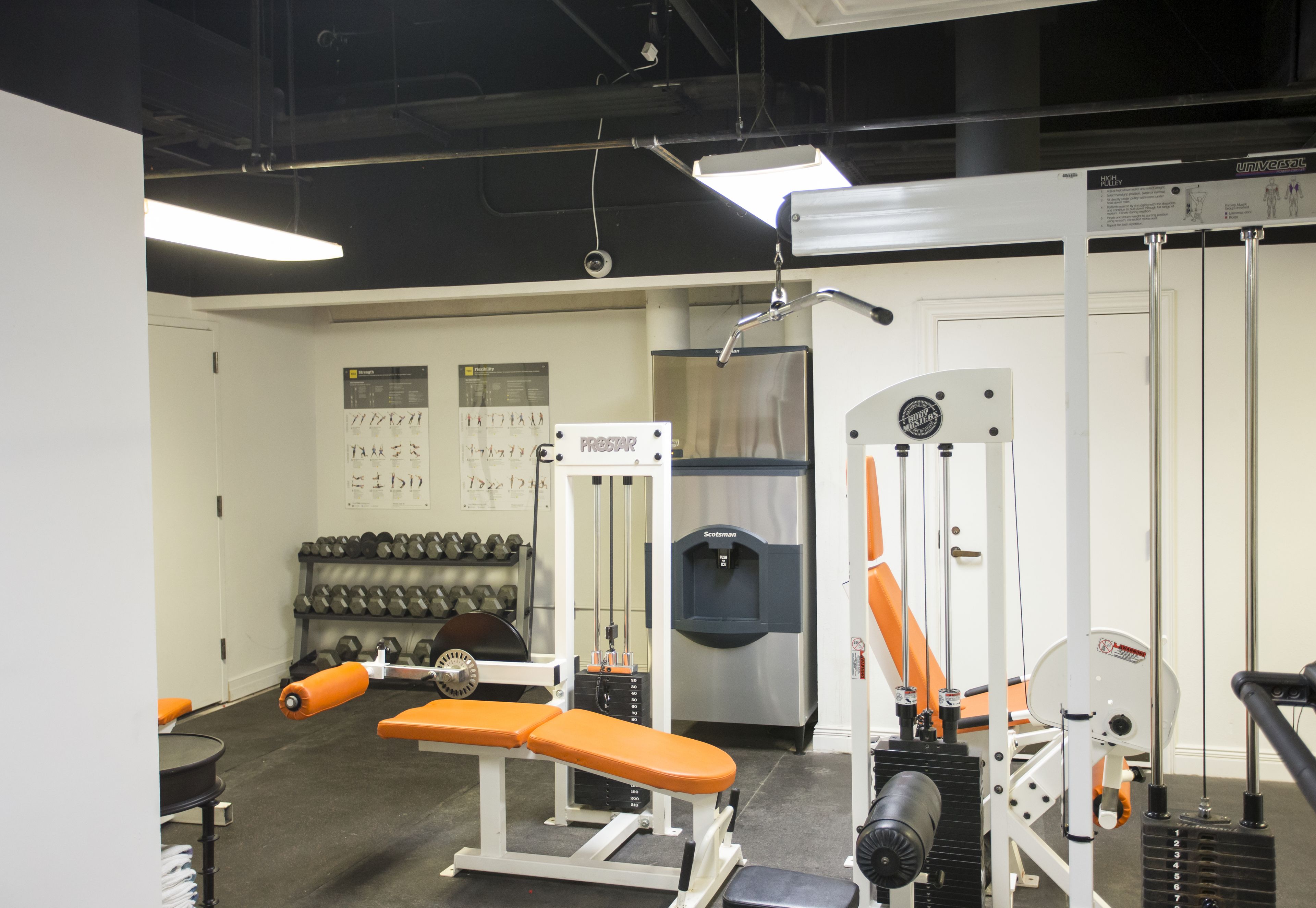 A gym with weightlifting equipment, dumbbells, and benches.