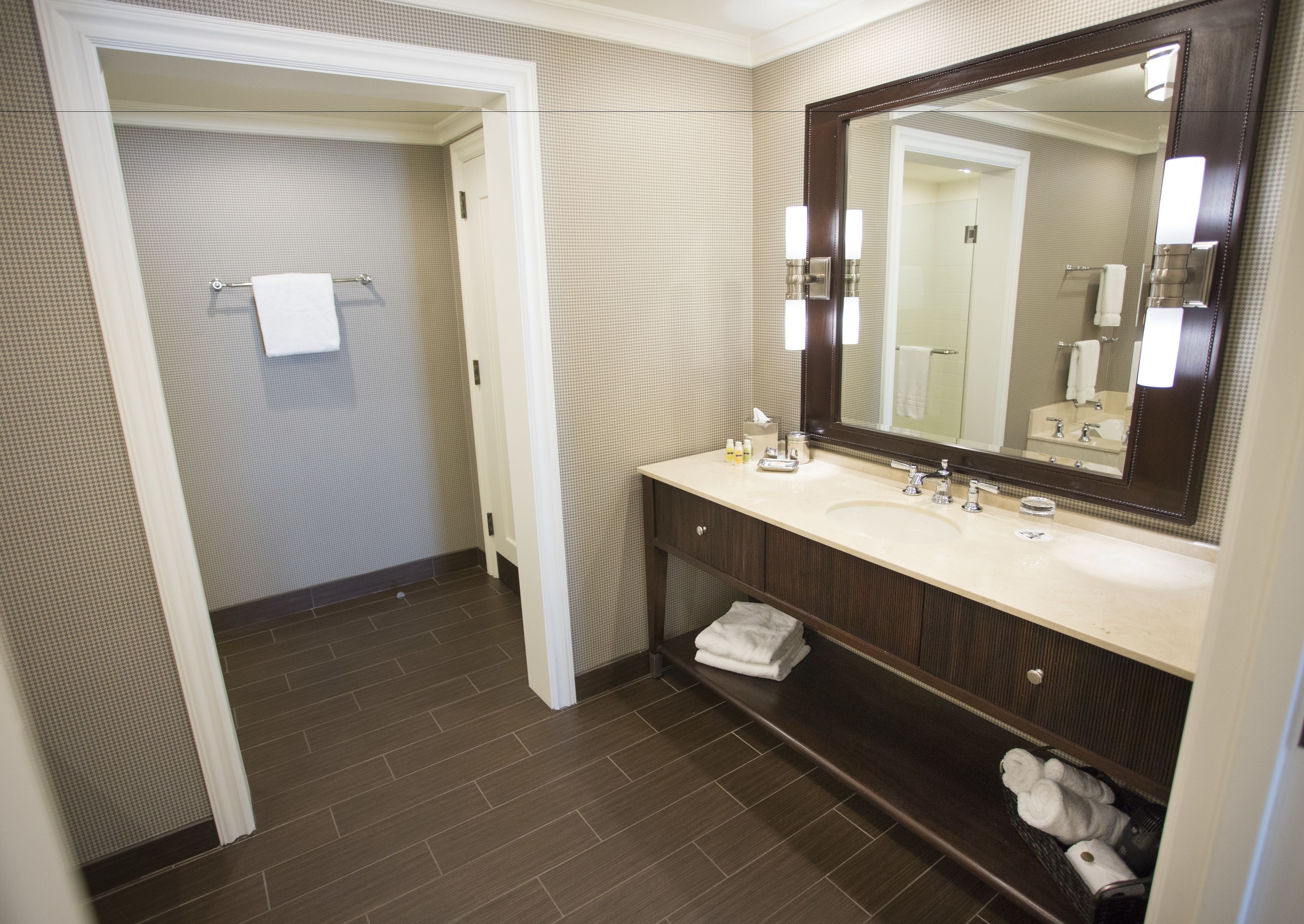 A bathroom with a large mirror, a sink, and a towel rack.
