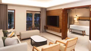 A modern hotel room with a sofa, armchair, flat-screen TV, and a bed.
