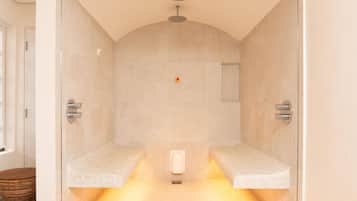 Un baño moderno con mampara de vidrio, dos lavamanos, ducha y toallero.