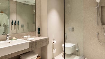 A modern bathroom with a glass-enclosed shower, a sink with a mirror, and toiletries.