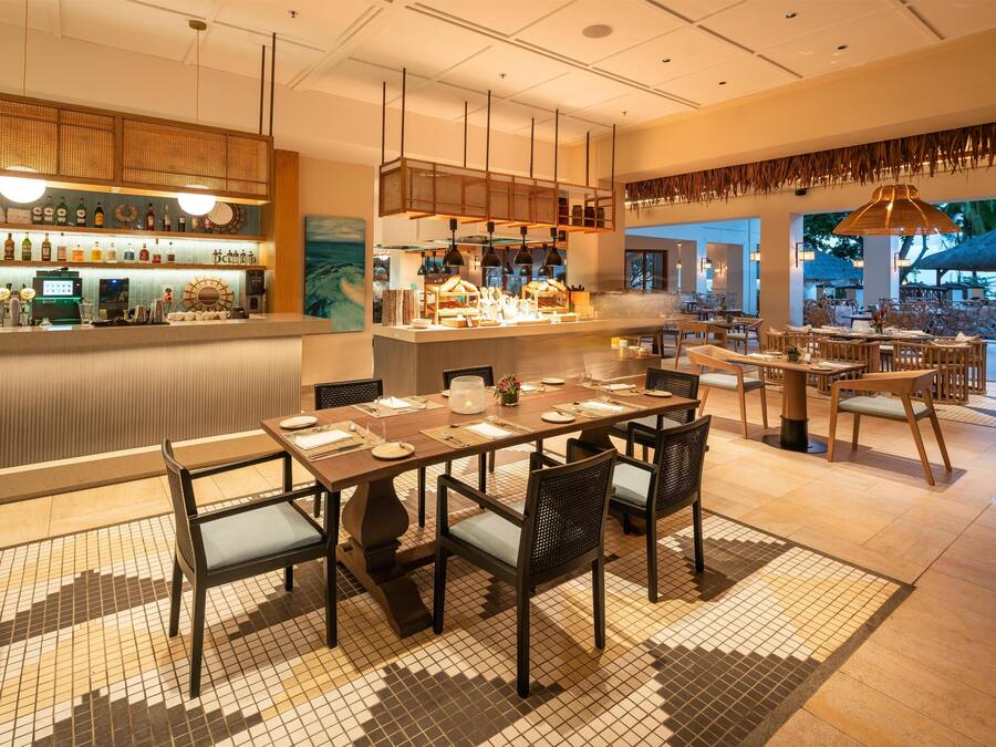 A restaurant with a bar area, multiple dining tables, and chairs.