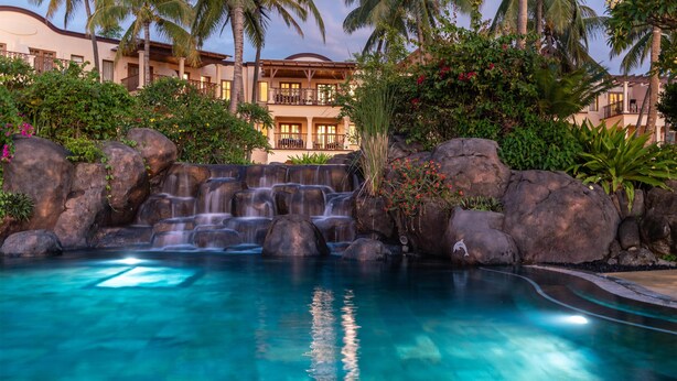 Ein Resort mit Pool, Palmen und einem Wasserfall.