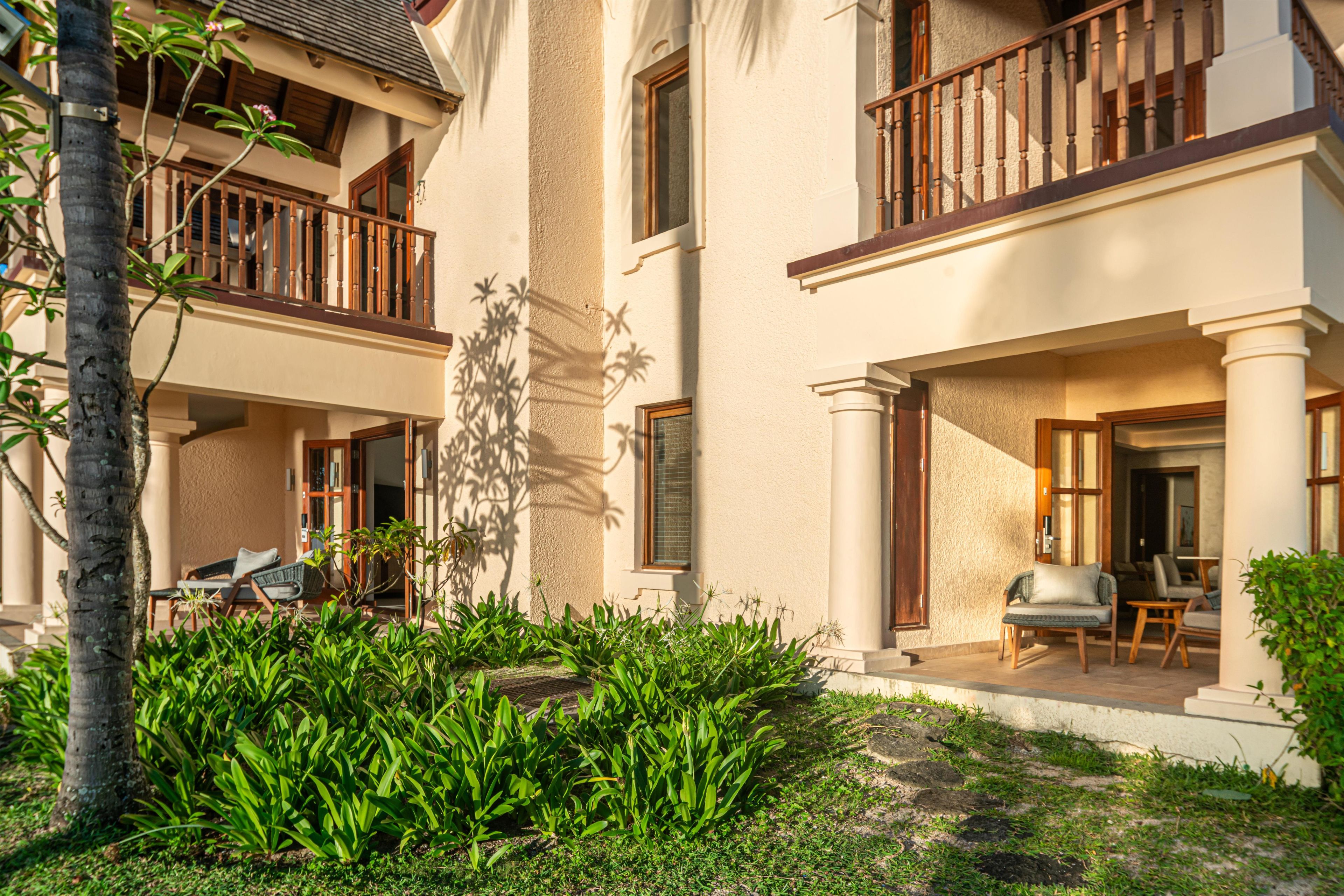 A two-story building with a balcony, a covered patio, and a garden area with plants.