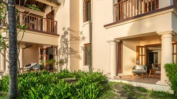 A two-story building with a balcony, a covered patio, and a garden area with plants.