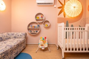 A baby room with a crib, a changing table, and a sofa. - Hilton Mauritius Resort & Spa (Flic-en-Flac)