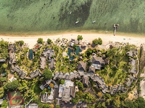 An aerial view of a resort with multiple buildings, a swimming pool, and a beach.