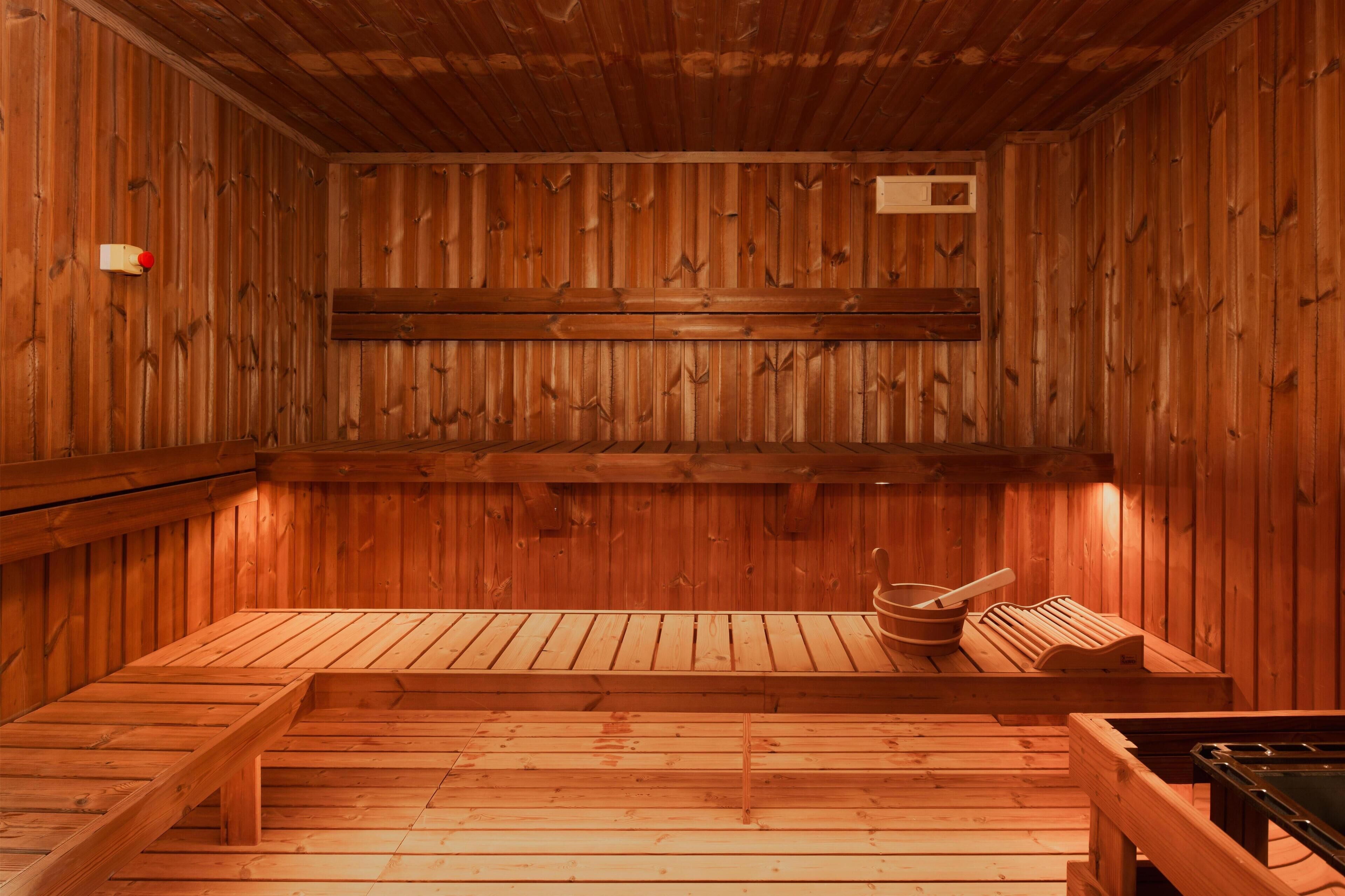 A wooden sauna with benches and a wooden bench with a bowl and spoon.