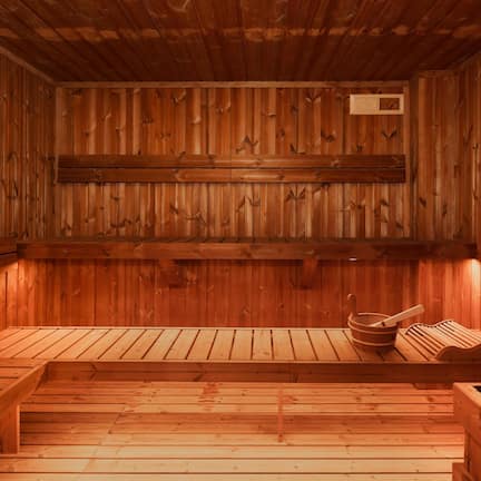 A wooden sauna with benches and a wooden bench with a bowl and spoon.