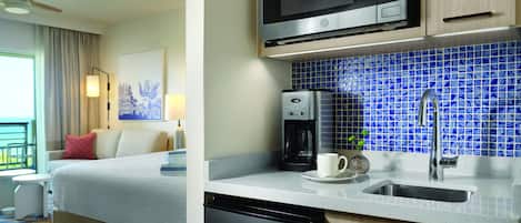 A hotel room with a bed, a coffee maker, a microwave, and a sink.