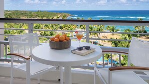 Un balcon avec une table, un saladier rempli d’oranges, une boisson et des lunettes de soleil.
