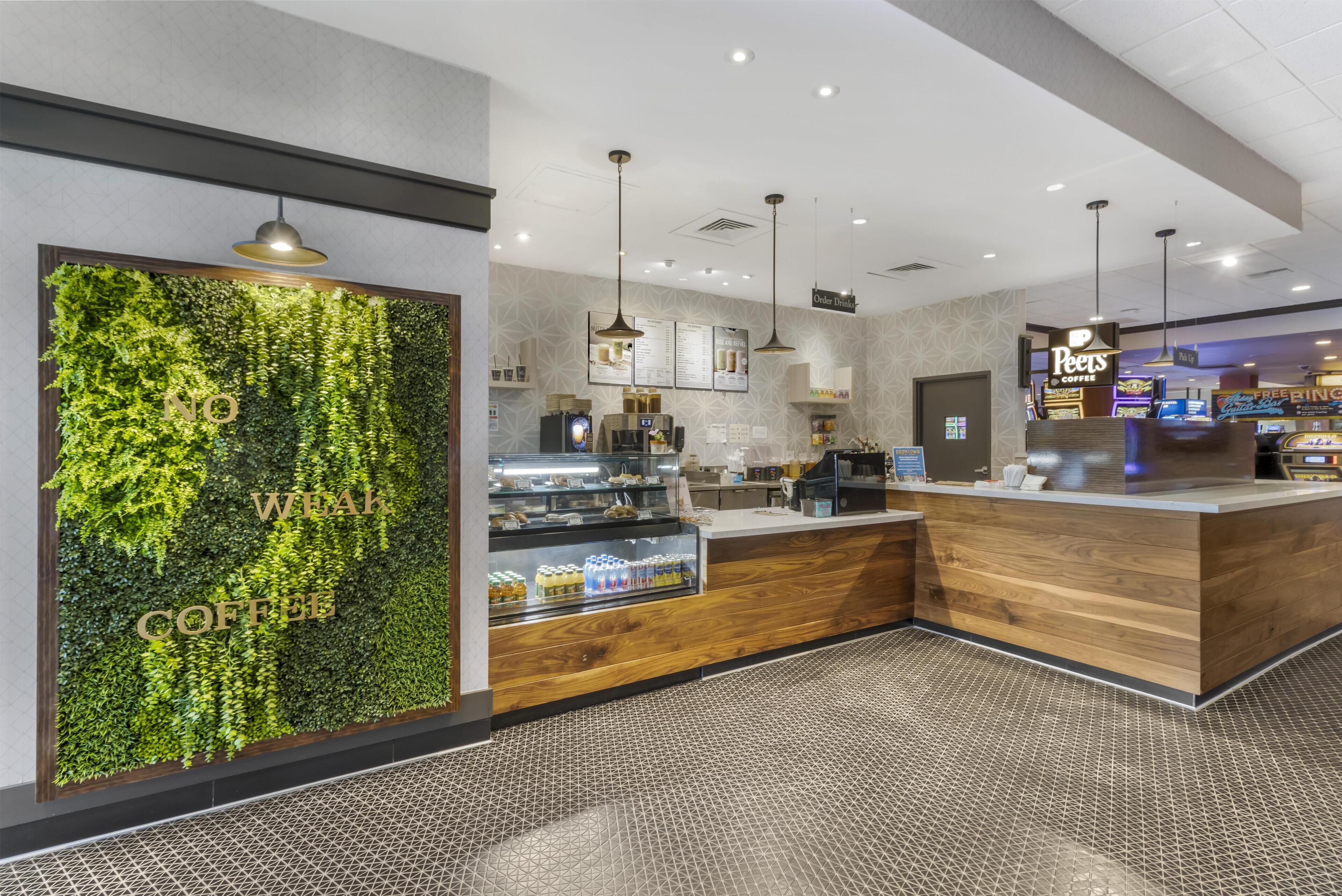 A modern coffee shop interior with a green wall, wooden counter, and menu display.
