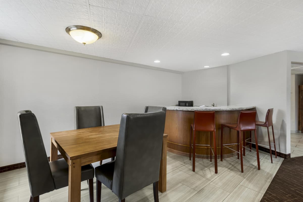 A modern dining area with a wooden table, black chairs, and a bar counter with stools.