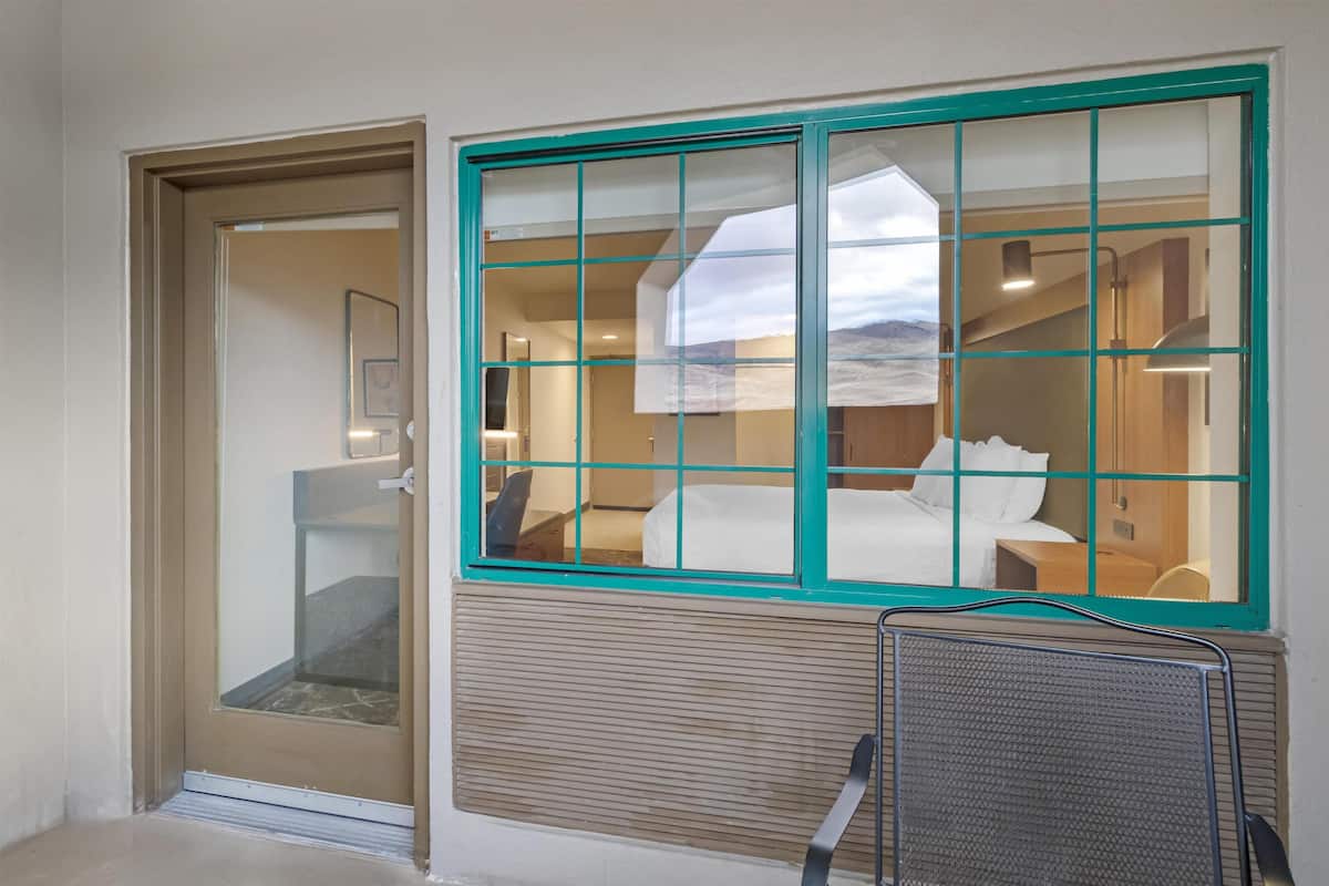 A hotel room with a sliding glass door, a window with a view, and a radiator.