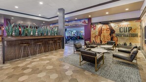 A lobby with a bar area, seating, and a mural.