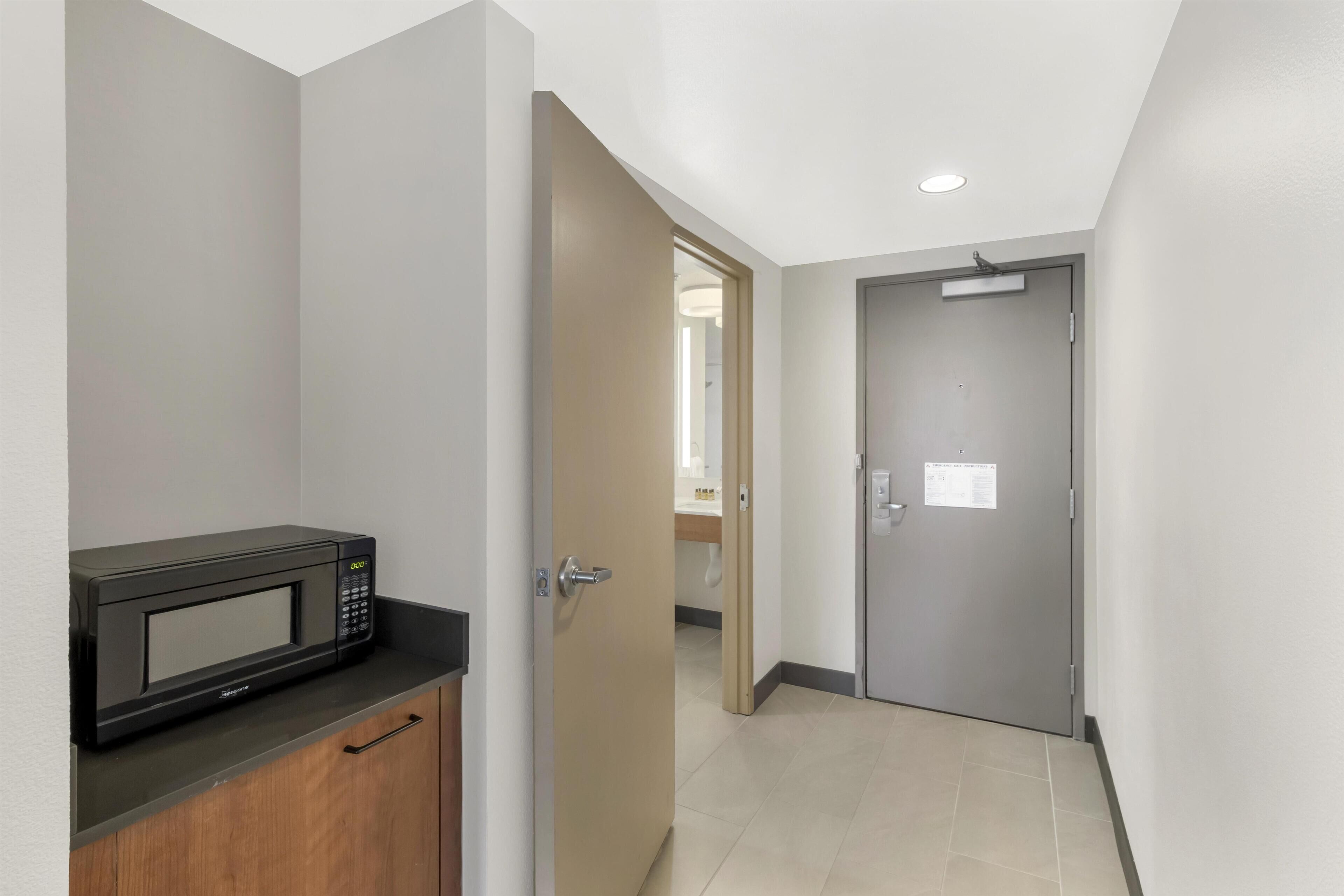 A hallway with a microwave on a counter, a door, and a tiled floor.