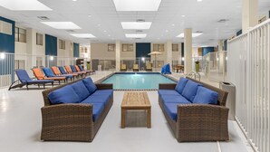 A pool area with lounge chairs, a pool table, and a seating area with wicker furniture.