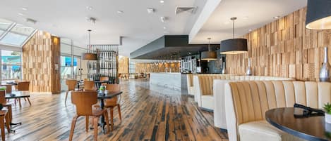 A spacious lobby with wooden flooring, seating areas, and a modern design.