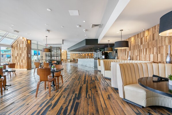 A spacious lobby with wooden flooring, seating areas, and a modern design.