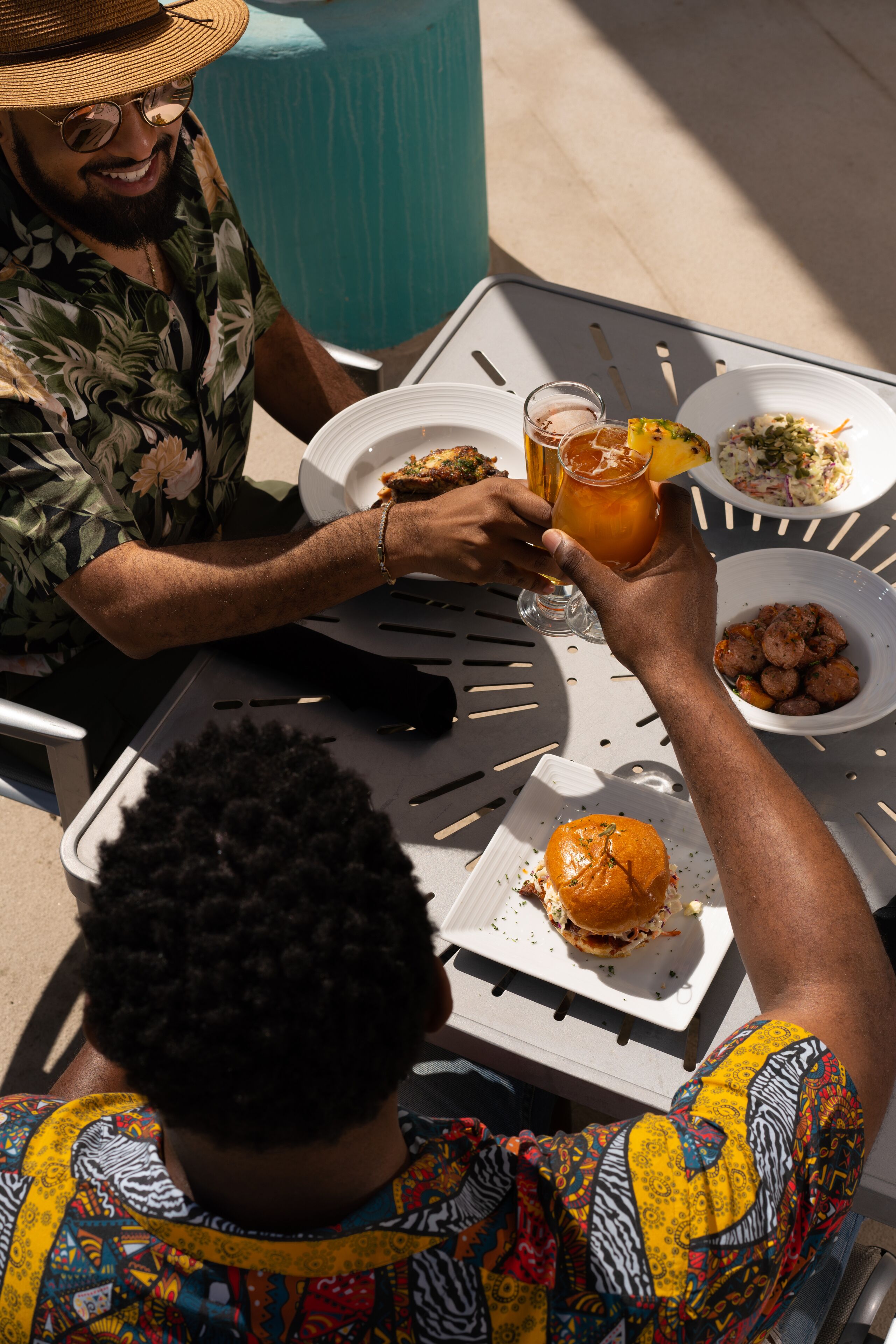 A dining table with plates of food, a drink, and a burger.