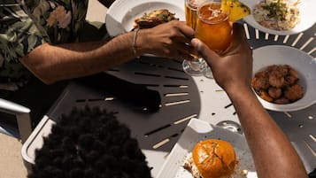 A dining table with plates of food, a drink, and a burger.
